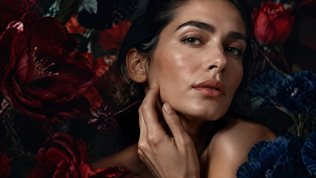 Serene close-up of a woman with calm luminous skin resting her fingertips near her jawline in a soft botanical setting