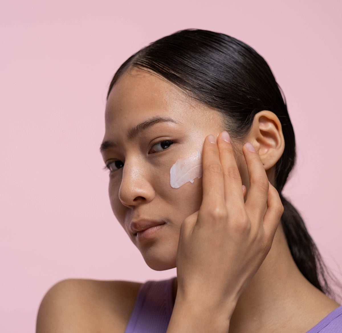 Woman applying cream to her face